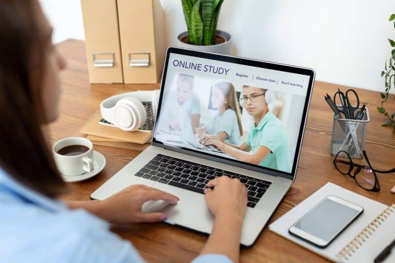 Woman studying online course on laptop, verifying program authenticity.